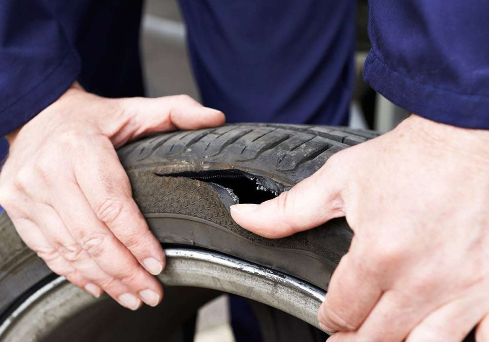 Close Up Of Mechanic Examining Damaged Car Tyre